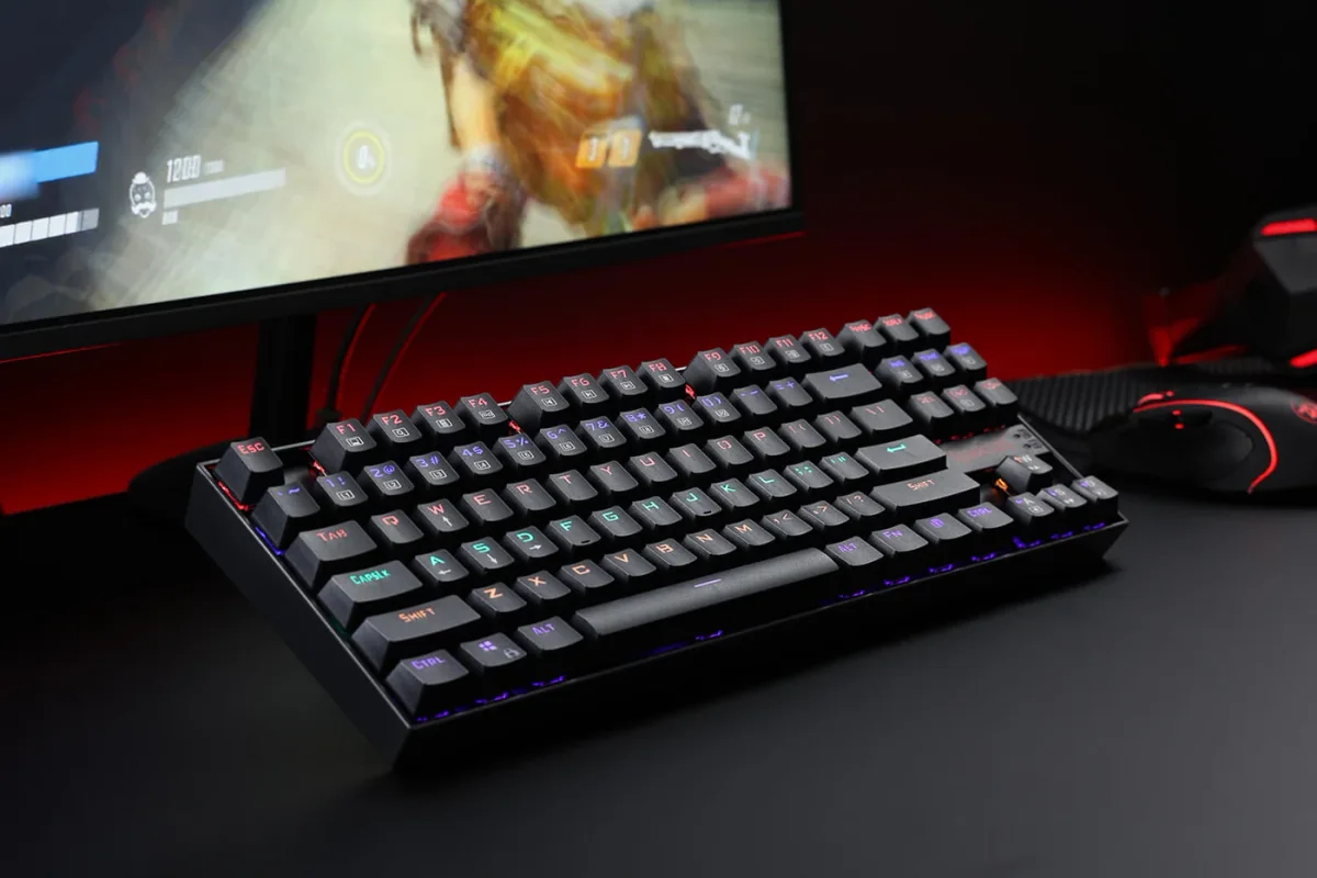 Redragon KUMARA K552 keyboard with colored backlighting on a dark gaming desk
