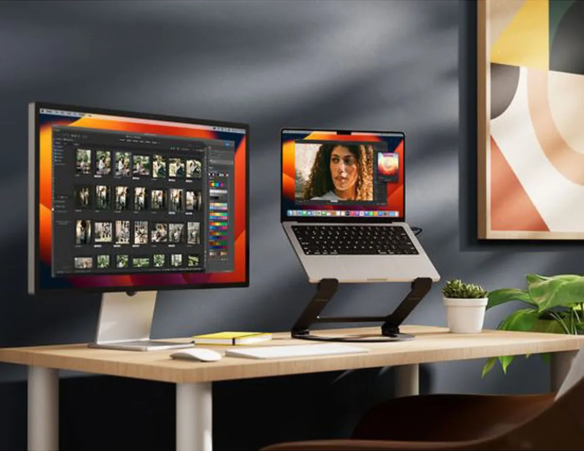 Twelve South Curve Flex elevating a MacBook beside a monitor on a wood desk